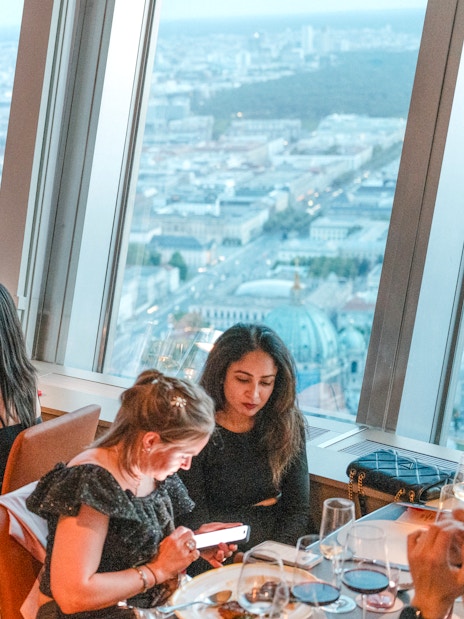 Guests dining at the Berlin TV Tower restaurant with city views.
