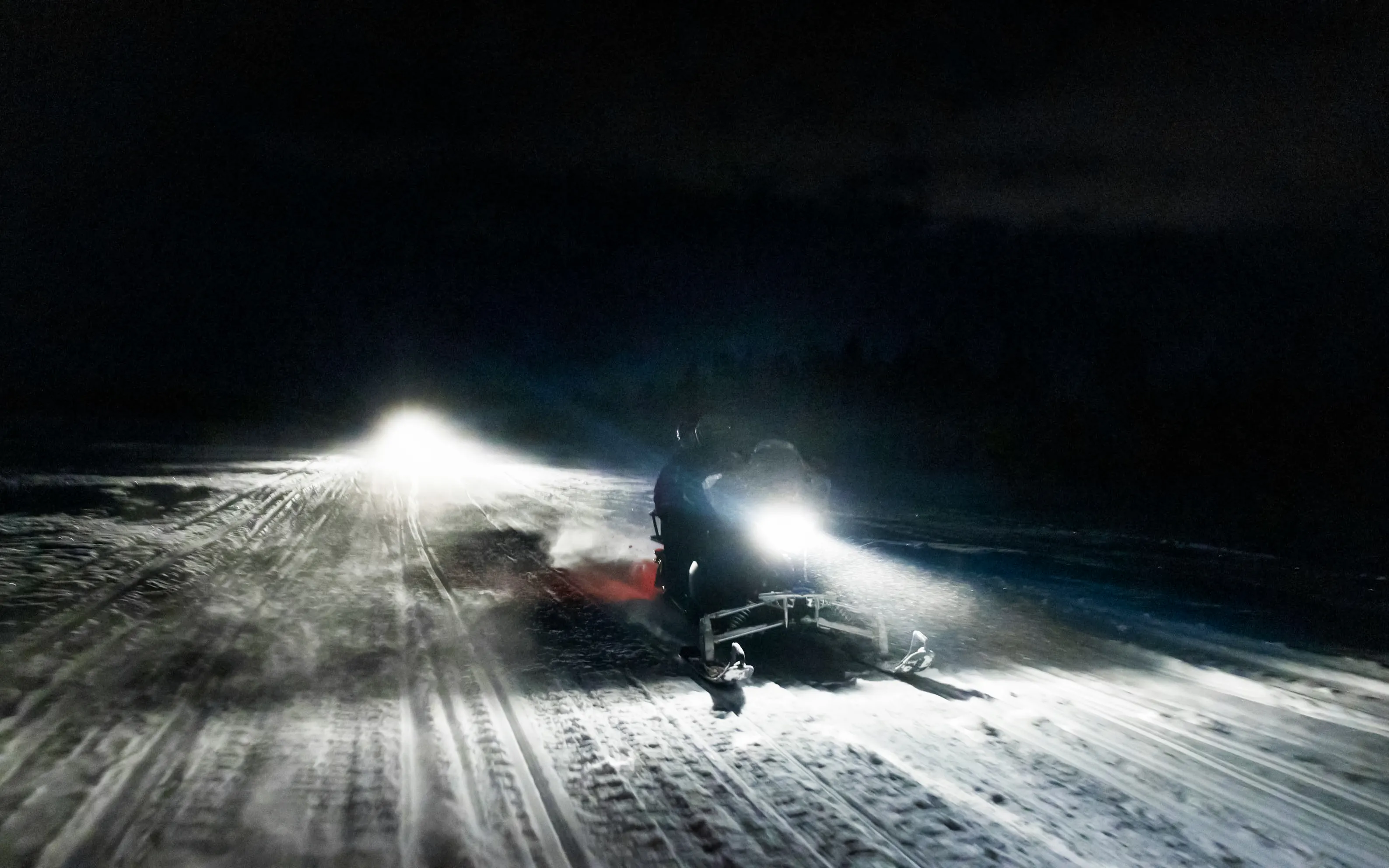 Snowmobile on snowy trail at night during Rovaniemi Northern Lights safari.