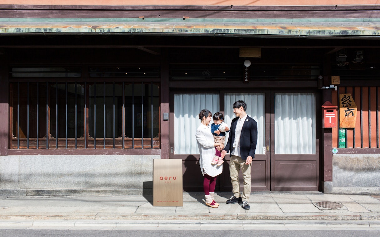Couple with child outside traditional Japanese building after tea ceremony.