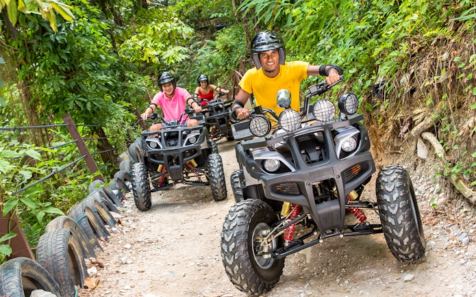 ATV riders on a forest trail at Sunway Lagoon theme park.