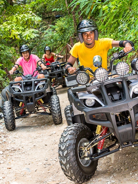 ATV riders on a forest trail at Sunway Lagoon theme park.