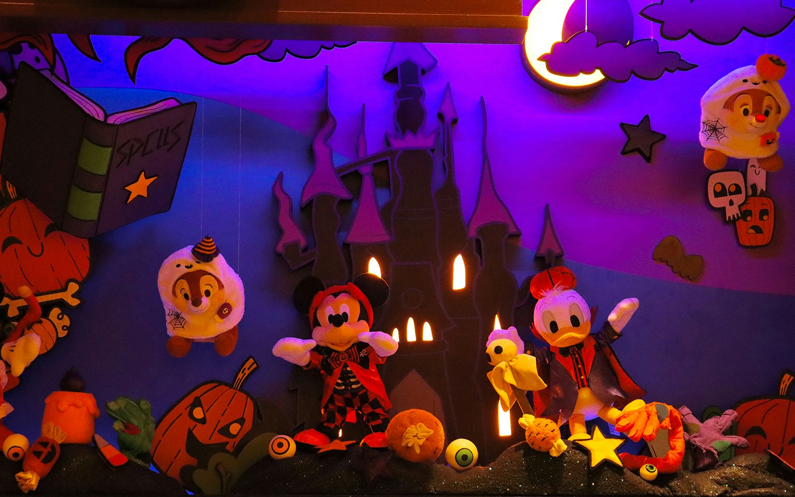 Disney characters in Halloween costumes at Disneyland Halloween party display.