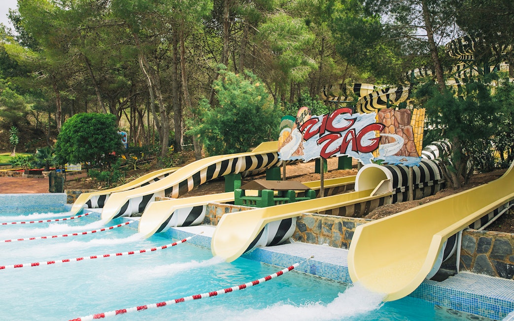 Zig Zag water slides at Aqualandia Benidorm surrounded by trees.