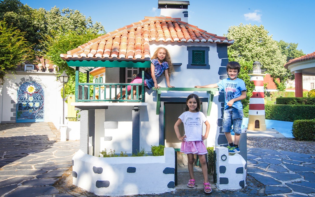 Children playing at Portugal dos Pequenitos with miniature buildings and lighthouse.