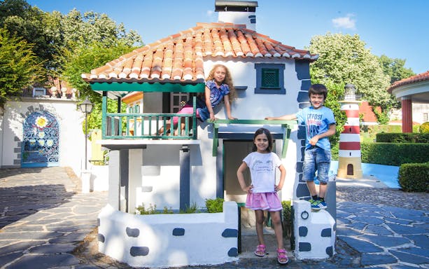 Children playing at Portugal dos Pequenitos with miniature buildings and lighthouse.
