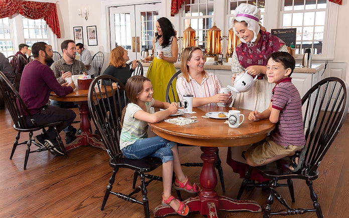 Tourists enjoying tea service at Abigail's Tea Room with a costumed server.