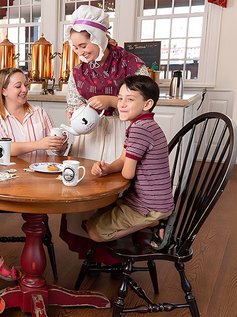 Tourists enjoying tea service at Abigail's Tea Room with a costumed server.