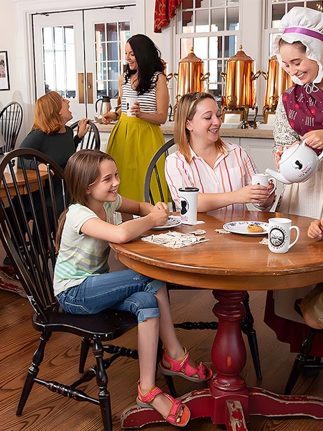 Tourists enjoying tea service at Abigail's Tea Room with a costumed server.