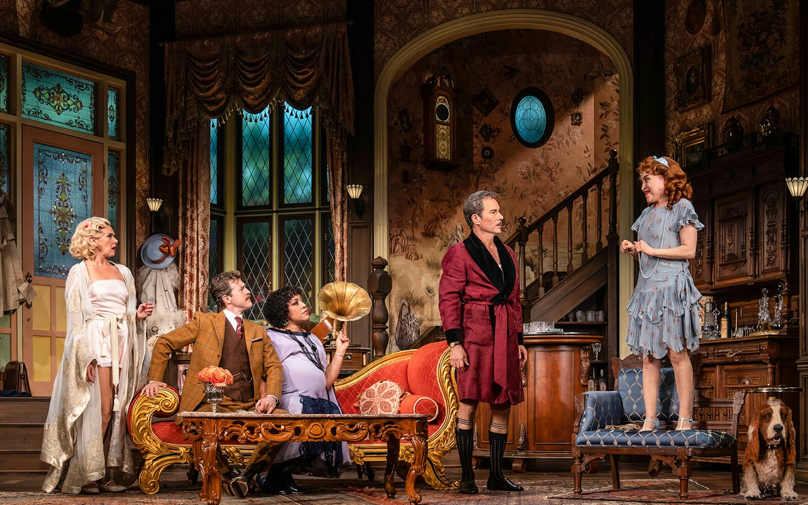 Actors performing a scene in a vintage living room set from "The Cottage" play.