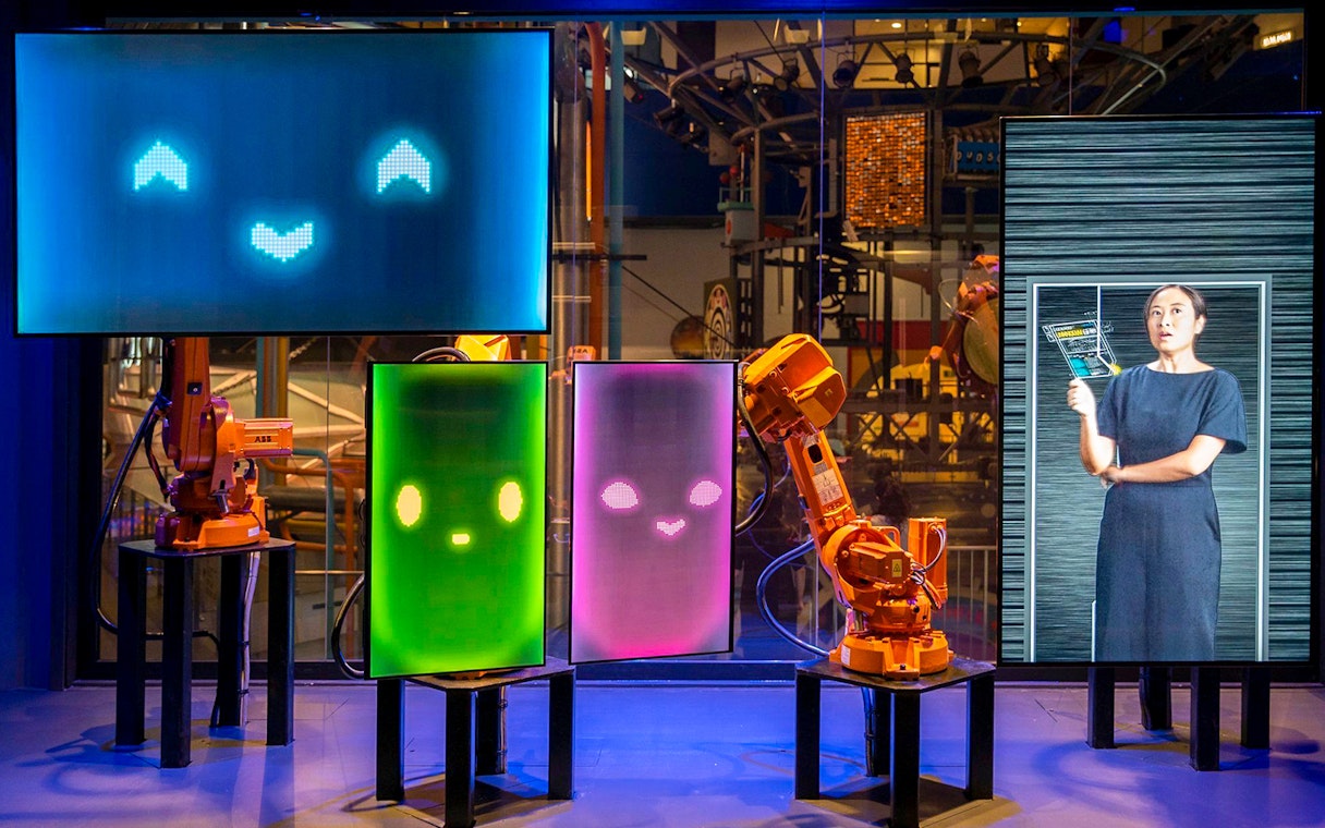 Interactive robot exhibit at Science Centre Singapore with digital screens and robotic arms.