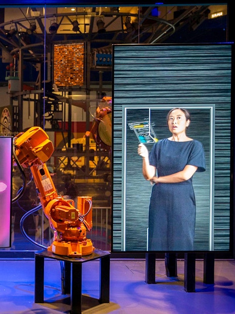 Interactive robot exhibit at Science Centre Singapore with digital screens and robotic arms.