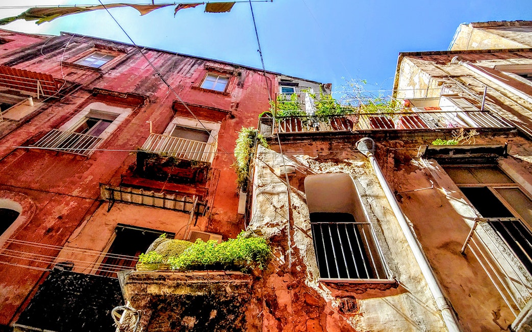 Old buildings with balconies in Naples, Italy, viewed from below on a sunny day.