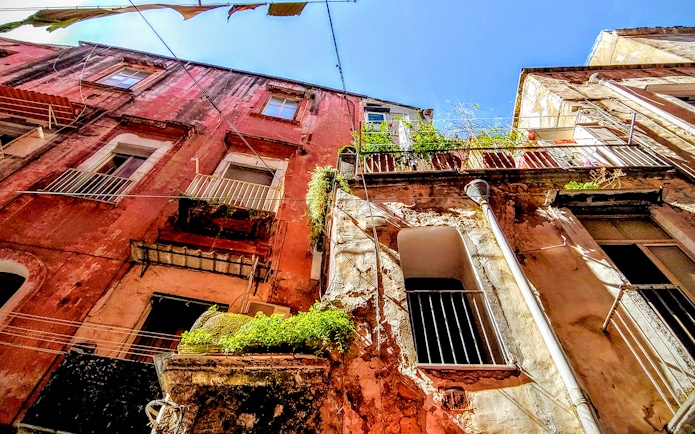 Old buildings with balconies in Naples, Italy, viewed from below on a sunny day.
