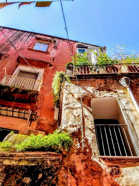 Old buildings with balconies in Naples, Italy, viewed from below on a sunny day.