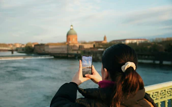 Person photographing the dome of La Grave Hospital in Toulouse along the Garonne River.