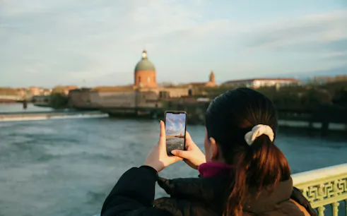 Person photographing the dome of La Grave Hospital in Toulouse along the Garonne River.