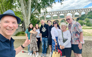 Group of tourists smiling in front of Pont du Gard, France.