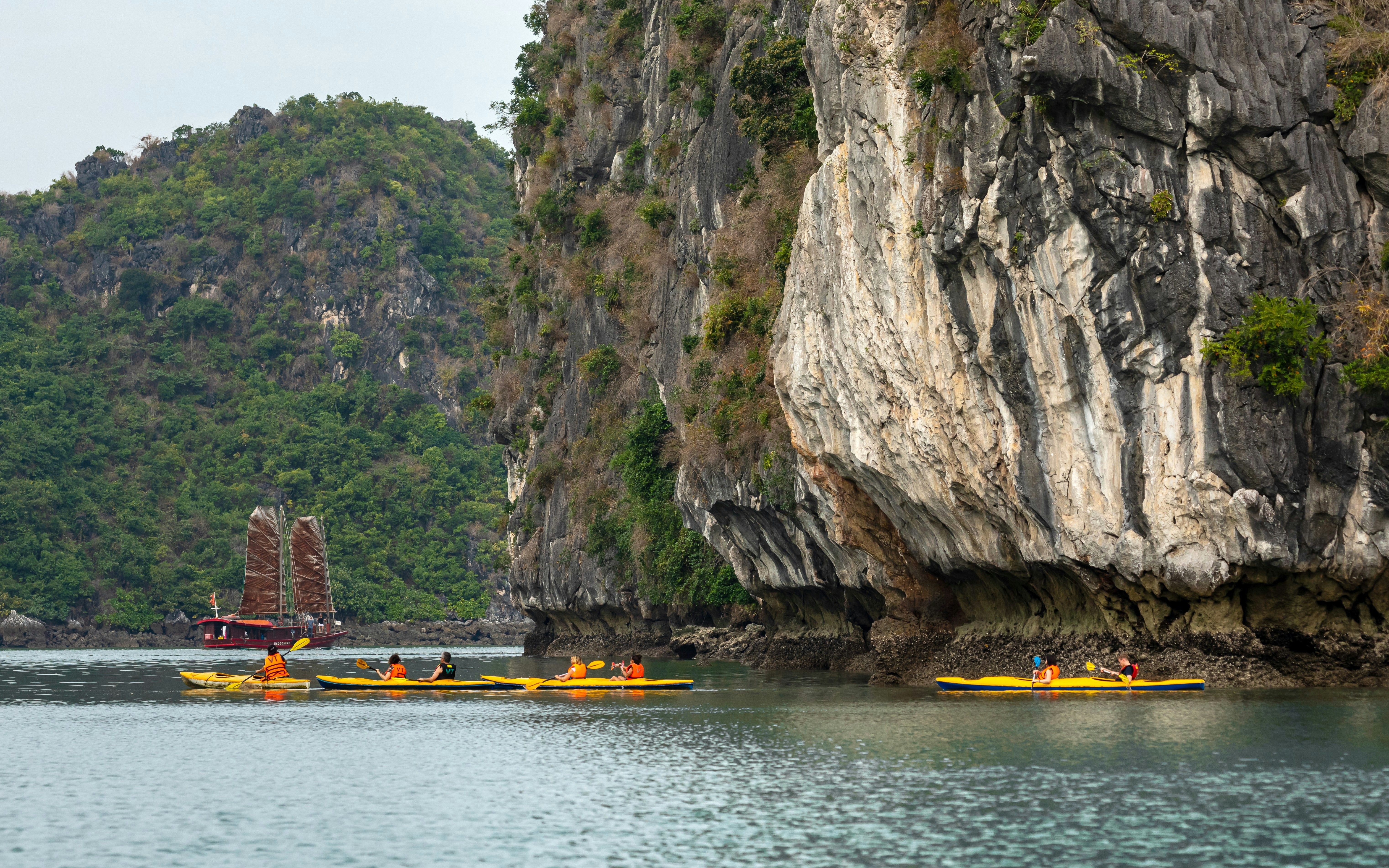 Kayakers exploring Luon Cave's limestone cliffs in Halong Bay, Vietnam.