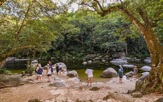 Group exploring Daintree Rainforest by a river with large rocks.