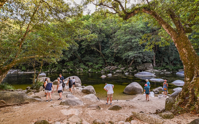 Group exploring Daintree Rainforest by a river with large rocks.