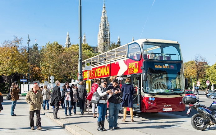 Vienna HopOn HopOff bus with tourists near Vienna City Hall.