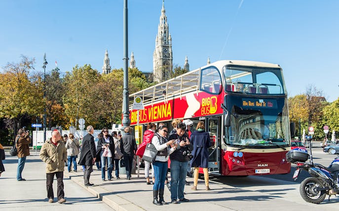 Vienna HopOn HopOff bus with tourists near Vienna City Hall.