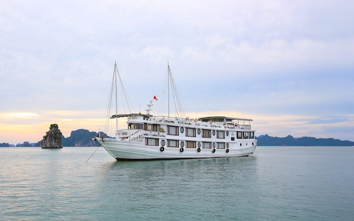 Cruise ship sailing in Halong Bay with limestone islands in the background.