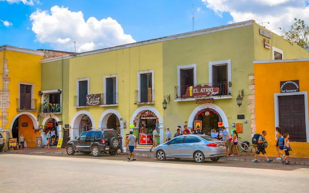 Valladolid street with colorful shops and people walking.