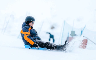 Person sledding on snow at Valle Nevado, Santiago tour.
