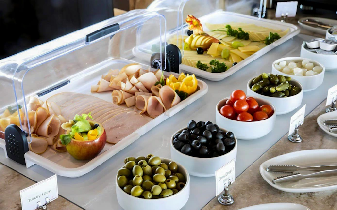 Buffet selection at Primeclass Lounge, Zurich Airport Terminal E, featuring meats, cheeses, and olives.