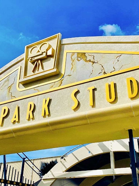 Movie Park Studios entrance gate with film camera icon under blue sky.