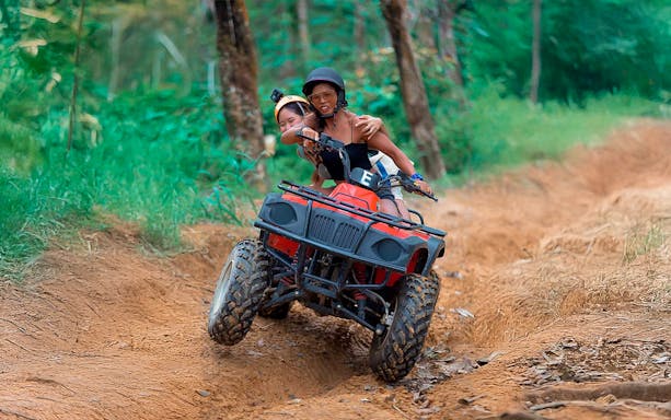 ATV riders navigating a dirt trail in Phuket forest.