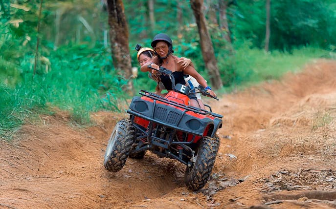 ATV riders navigating a dirt trail in Phuket forest.
