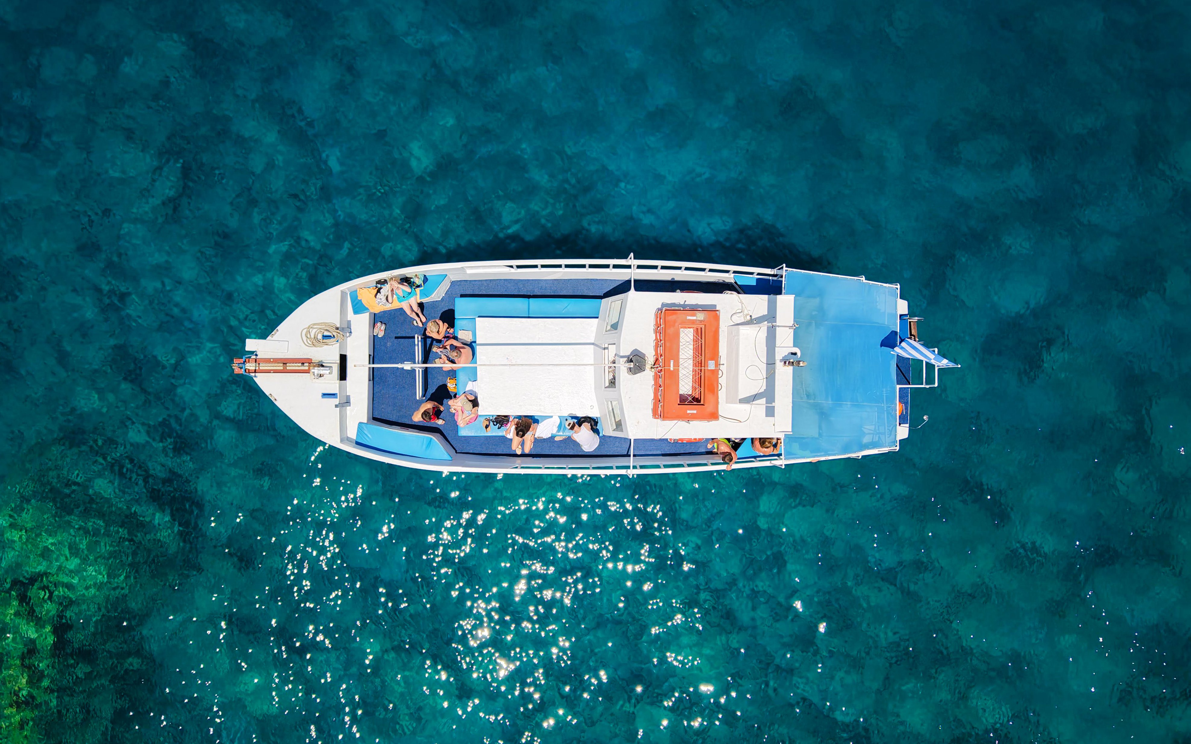 Guests relaxing on a boat during a Rhodes cruise over clear blue water.