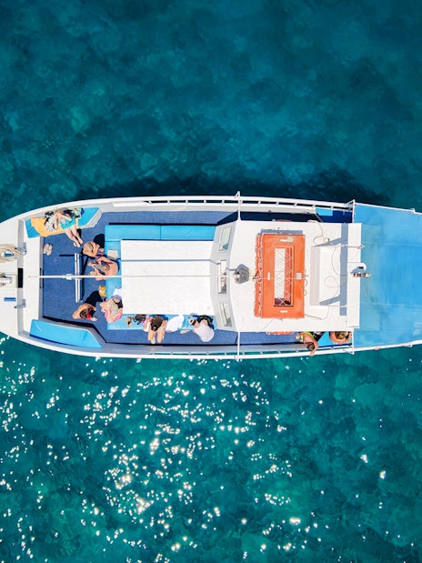 Guests relaxing on a boat during a Rhodes cruise over clear blue water.