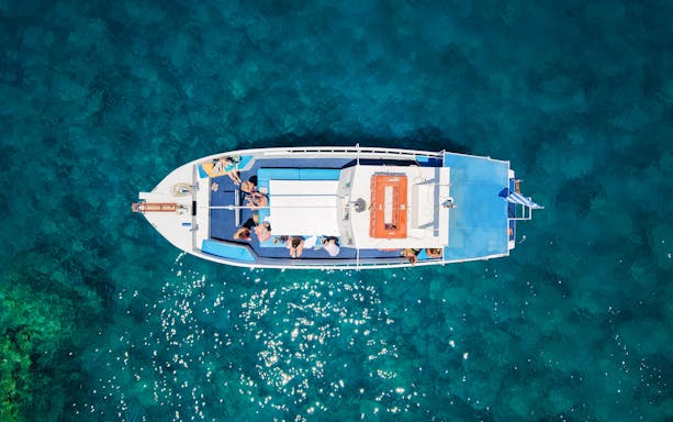 Guests relaxing on a boat during a Rhodes cruise over clear blue water.