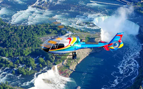 Helicopter flying over Niagara Falls with a view of the waterfalls and surrounding landscape.