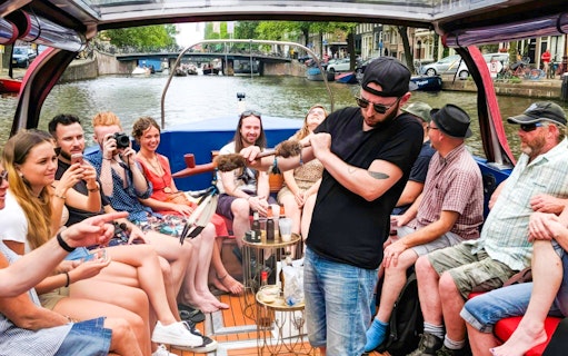 Amsterdam canal cruise with people enjoying a covered heated boat, featuring a musician playing.