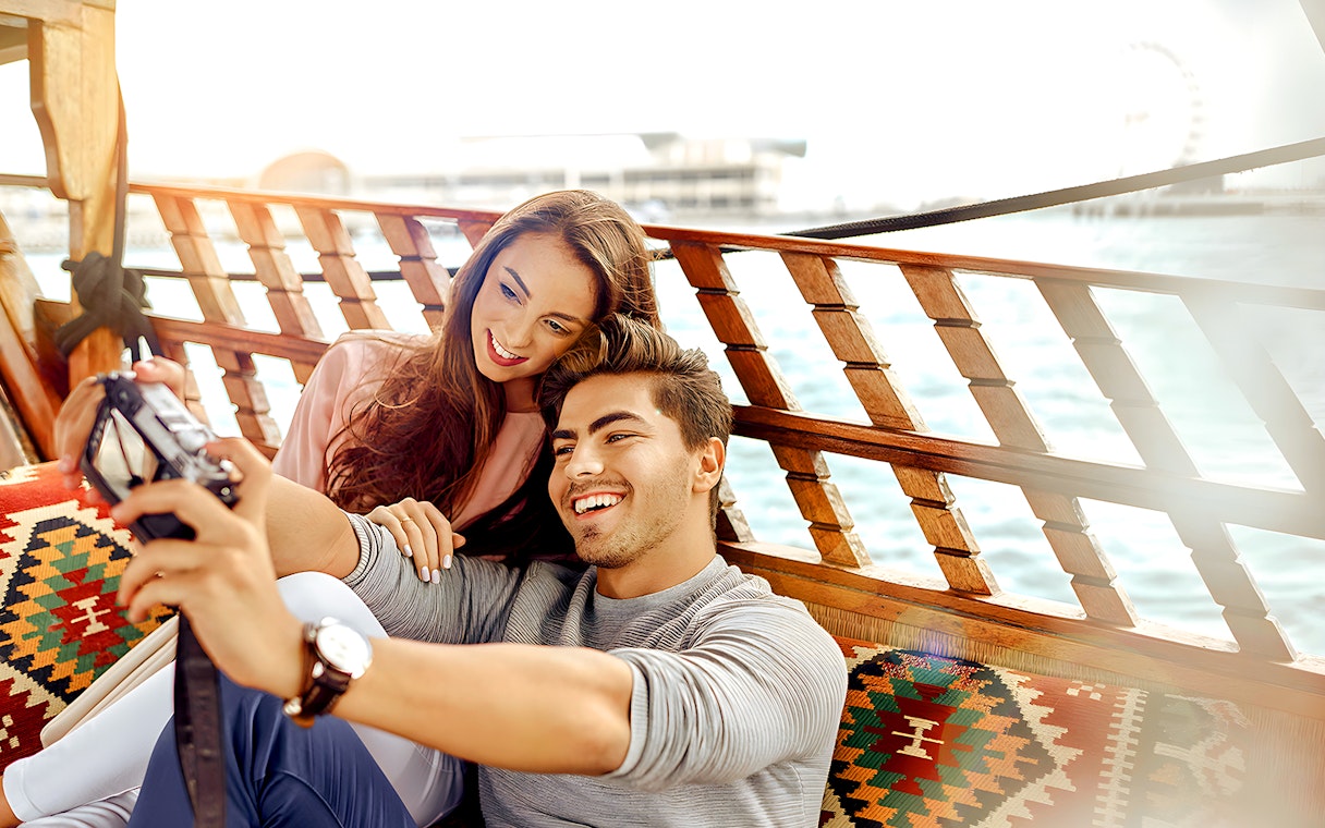 Couple taking a selfie on an abra boat during a Dubai Canal sightseeing tour.