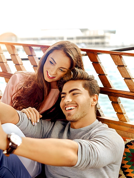 Couple taking a selfie on an abra boat during a Dubai Canal sightseeing tour.