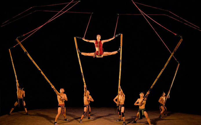 Performers using bamboo poles at Teh Dar Vietnamese Bamboo Circus under a dome.