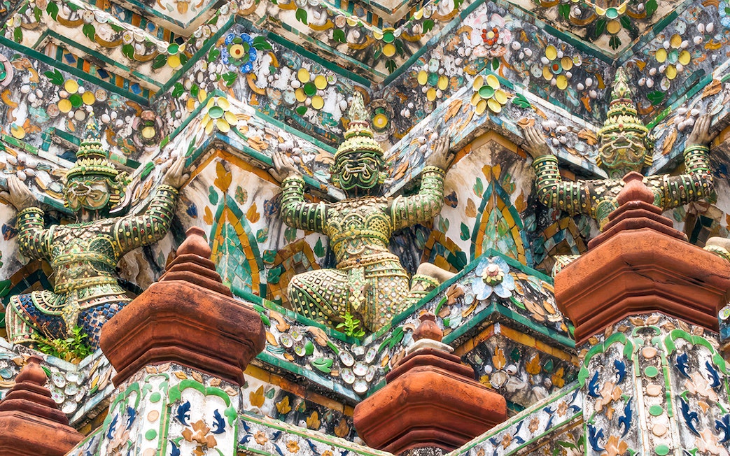 Wat Arun temple intricate sculptures on a guided walking tour in Bangkok, Thailand.