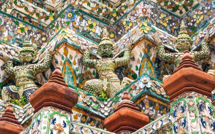 Wat Arun temple intricate sculptures on a guided walking tour in Bangkok, Thailand.