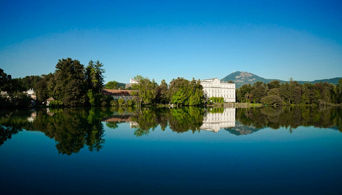 Leopoldskron Palace reflecting in a lake with mountains in Salzburg, Austria.