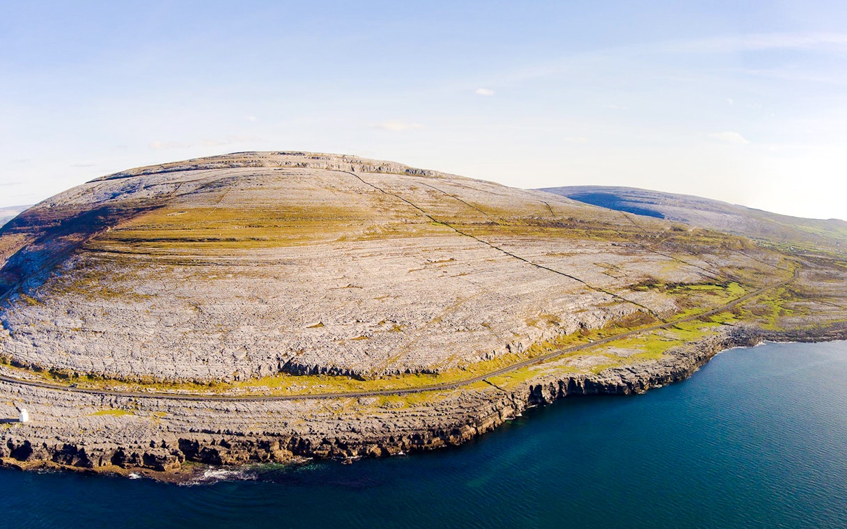 Aerial view of the rocky landscape of the Burren, Ireland, with coastal cliffs and limestone terrain.