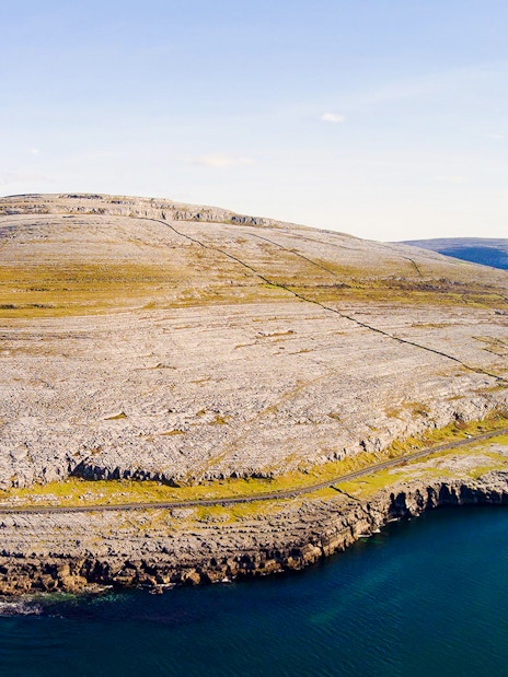 Aerial view of the rocky landscape of the Burren, Ireland, with coastal cliffs and limestone terrain.