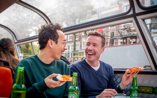 Two people enjoying pizza and drinks on an Amsterdam canal cruise.