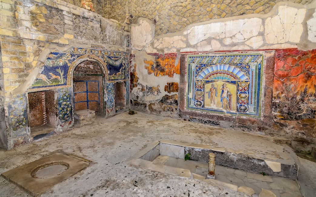 Remains of Herculaneum house interiors with frescoes and mosaics on walls.