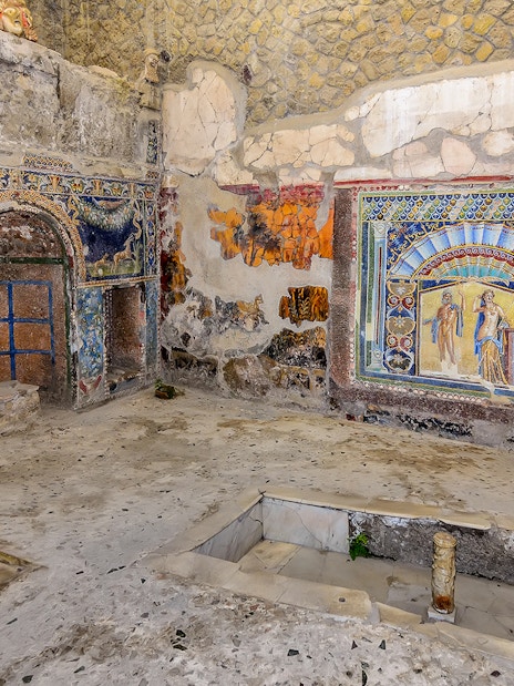 Remains of Herculaneum house interiors with frescoes and mosaics on walls.