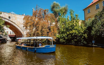 Sightseeing cruise boat on Devils Channel in Prague passing under a stone bridge.